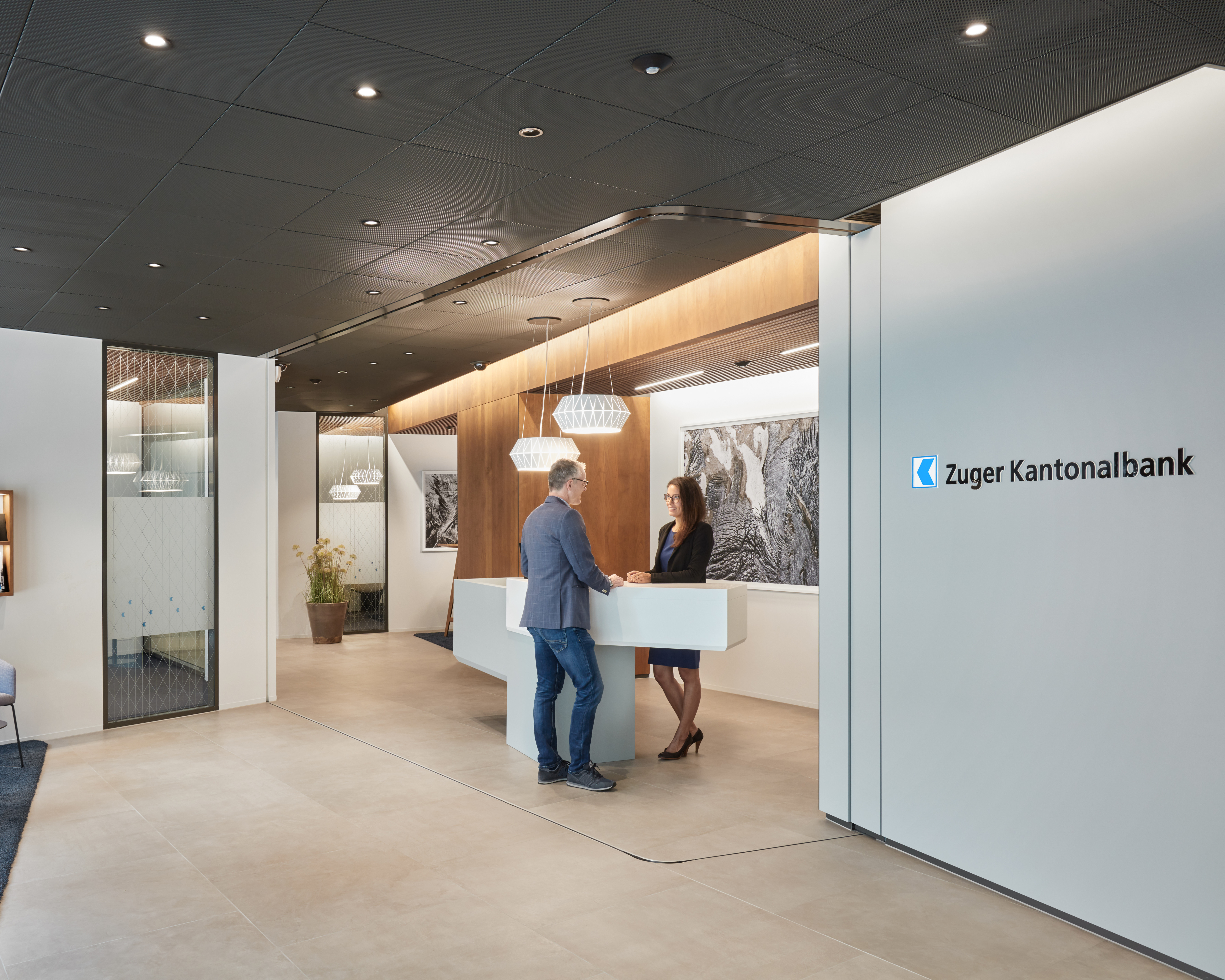 Man stands with woman at the counter in a branch of Zuger Kantonalbank